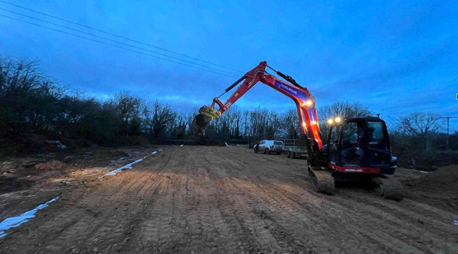 Excavator levelling the site at dusk